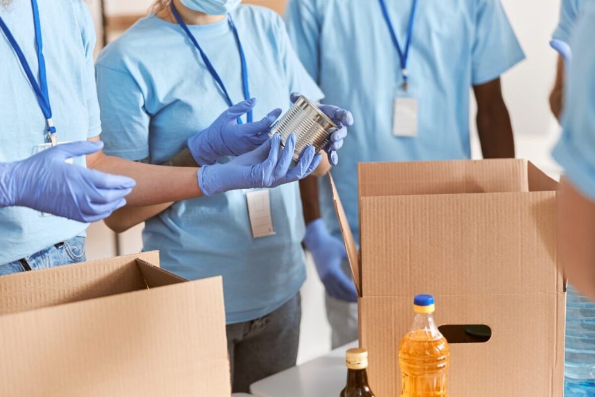 cropped-shot-volunteers-blue-uniform-protective-masks-gloves-sorting-packing-canned-food