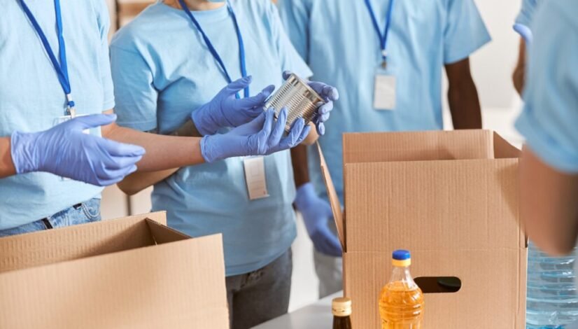 cropped-shot-volunteers-blue-uniform-protective-masks-gloves-sorting-packing-canned-food