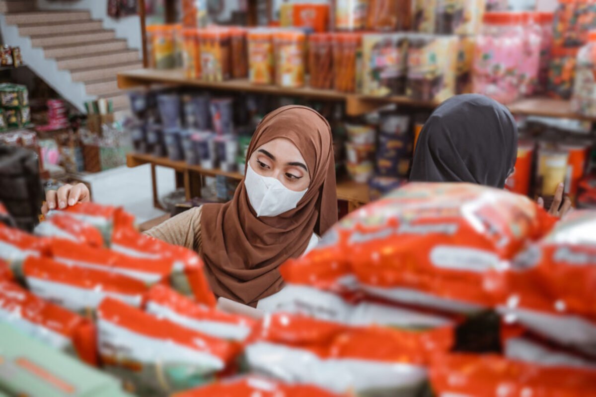 Muslim girl in mask choosing items while shopping in store